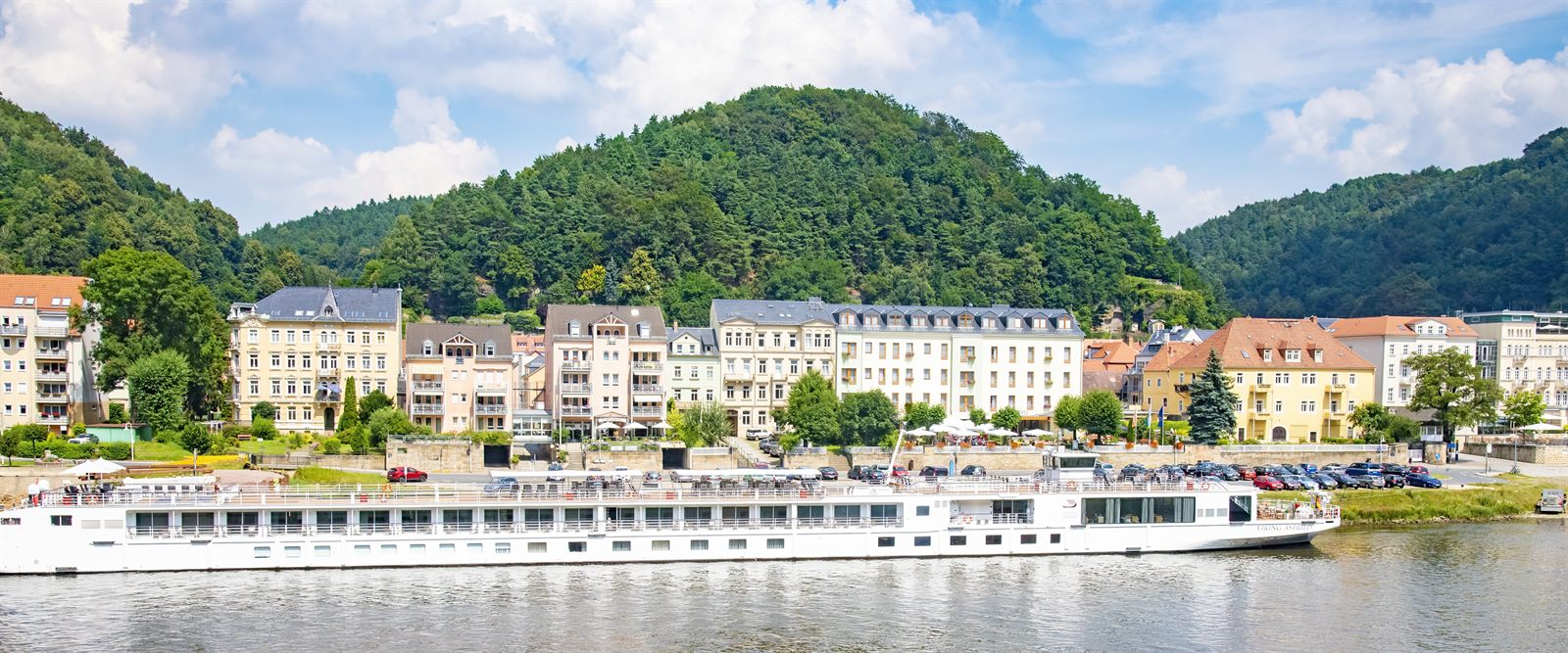 River cruise ship moored below green hills